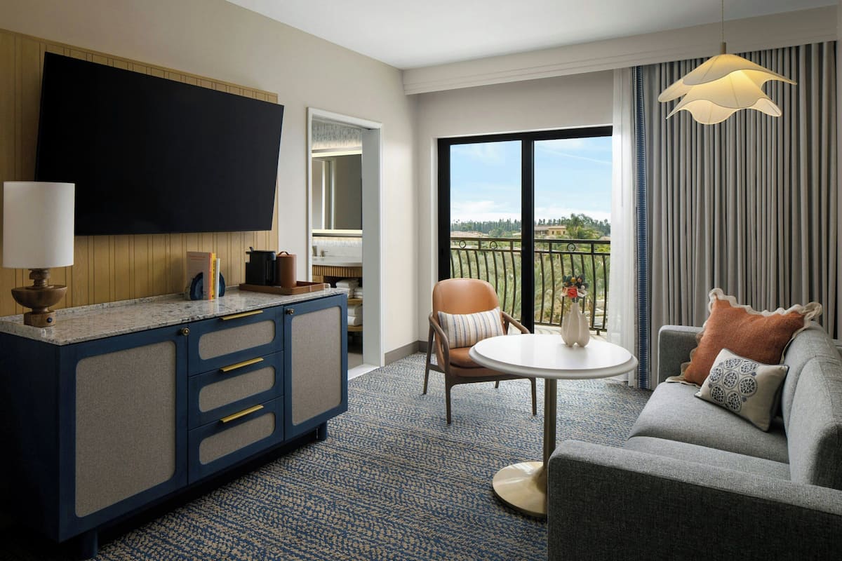 Ein Hotelzimmer mit Flachbildfernseher, einer Küchenzeile, einem Sofa, einem Esstisch und einem Balkon mit Aussicht.
