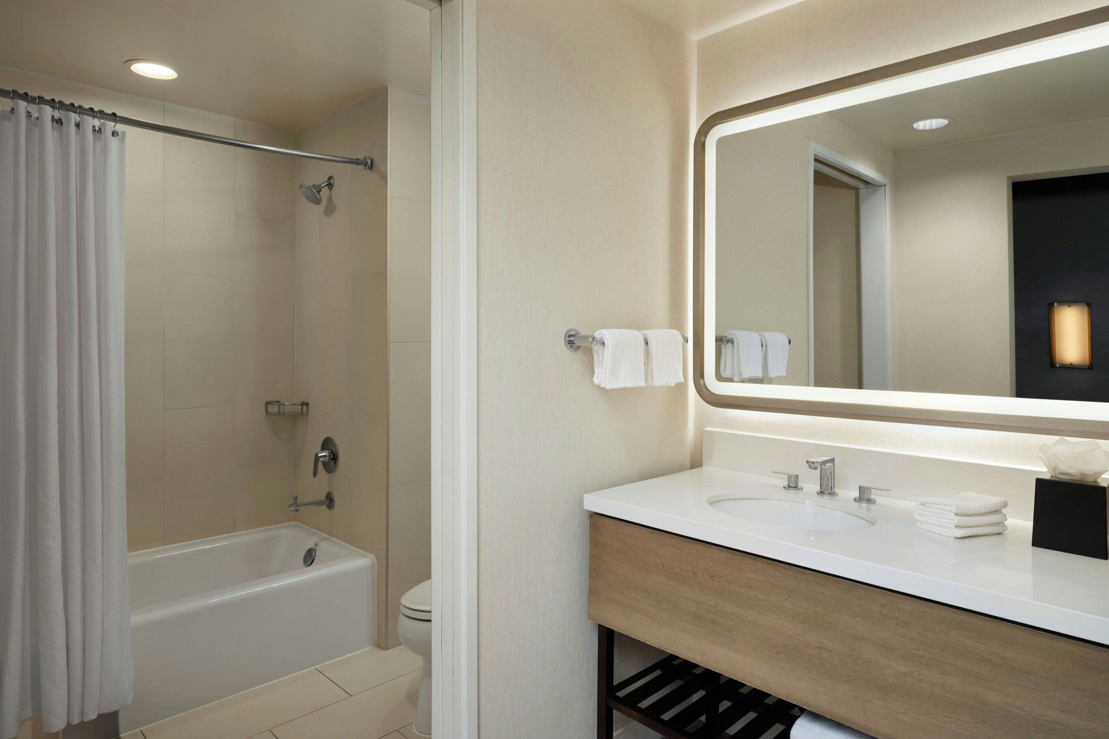 Un baño moderno con bañera, lavamanos y espejo.