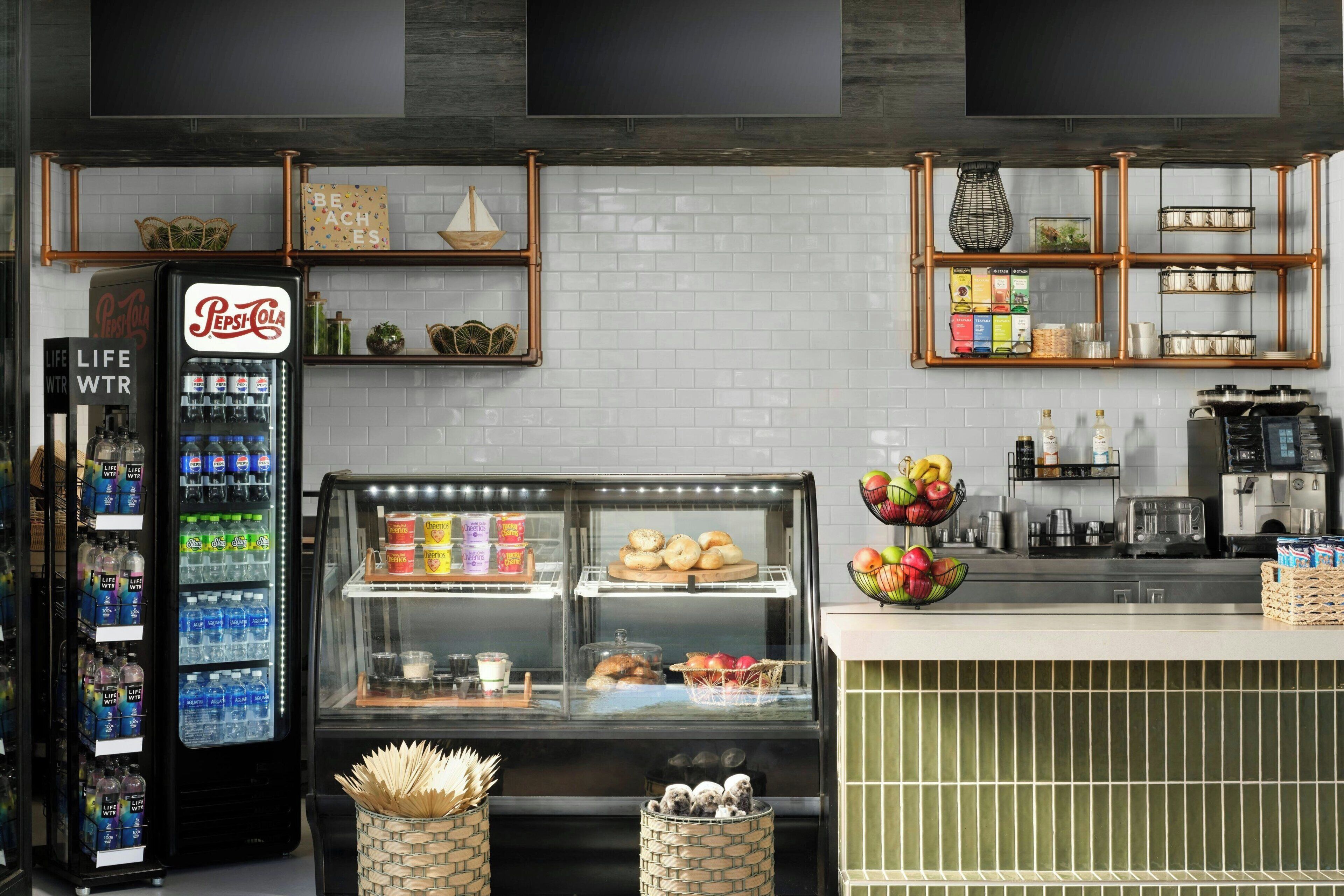 Una cocina industrial con un refrigerador, estanterías y un expositor.