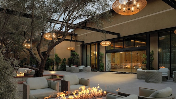 Un patio al aire libre con fogones, mobiliario de mimbre e iluminación colgante.