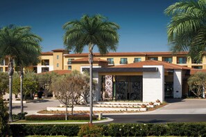 A hotel with a central courtyard, palm trees, and a building with a tiled roof. - Hotel Solea, Autograph Collection (Carlsbad)