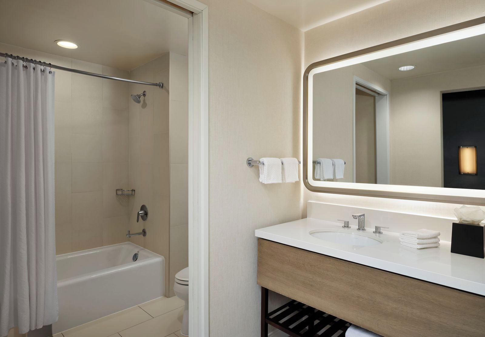 A modern bathroom with a bathtub, toilet, and a vanity with a mirror.