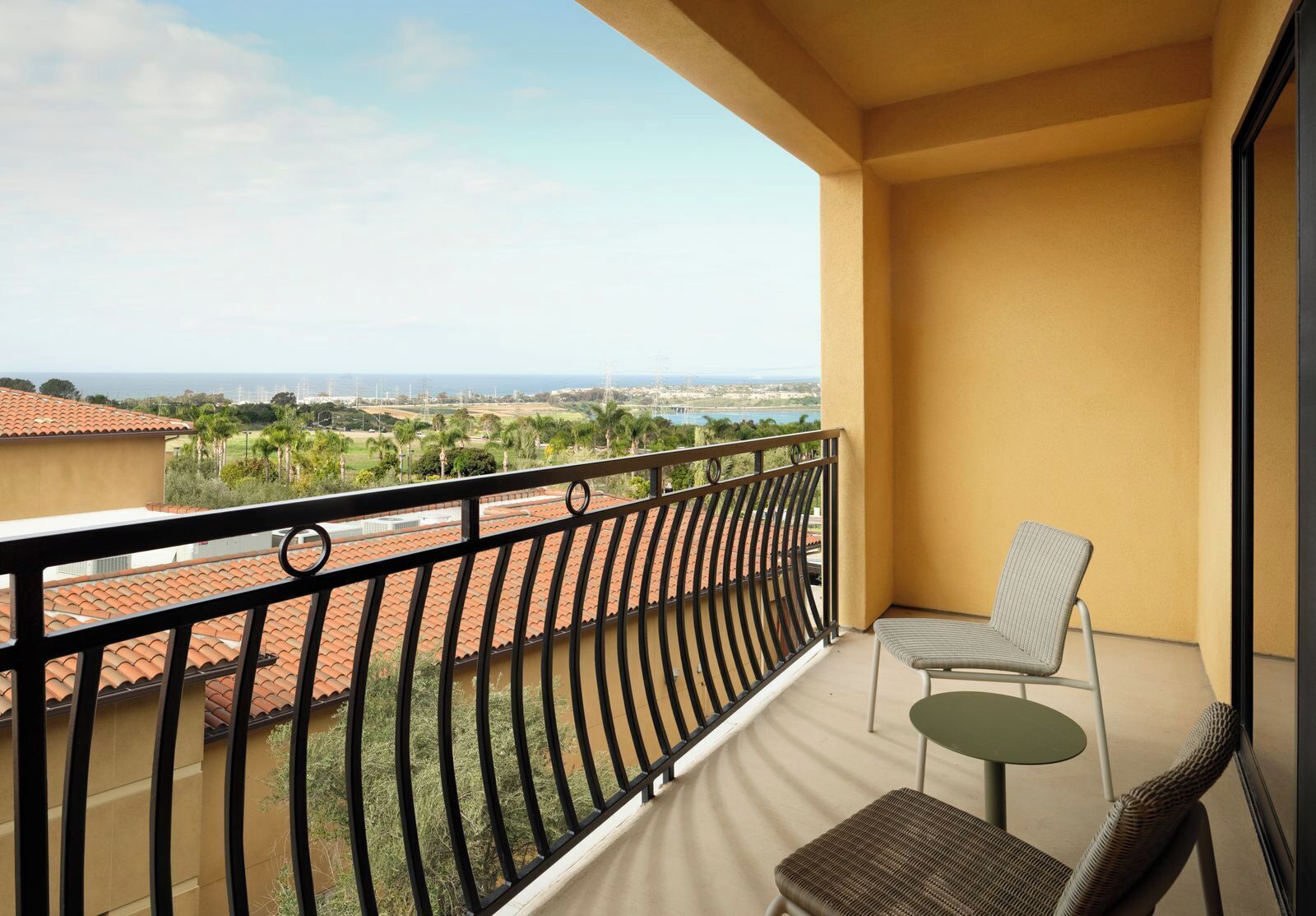 A balcony with a view of a cityscape, a chair, and a small table.