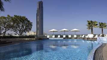 Una piscina al aire libre, sombrillas, sillones reclinables de piscina