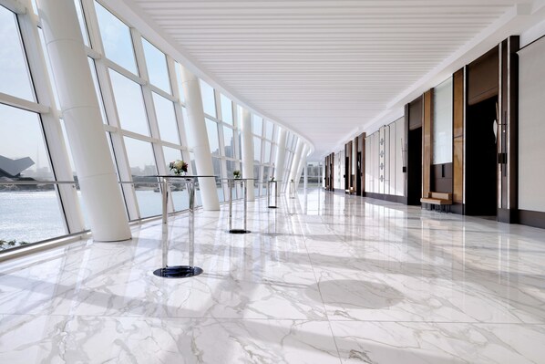 A spacious corridor with large windows, a polished marble floor, and a view of a body of water. - Crowne Plaza Festival City by IHG (Dubai)