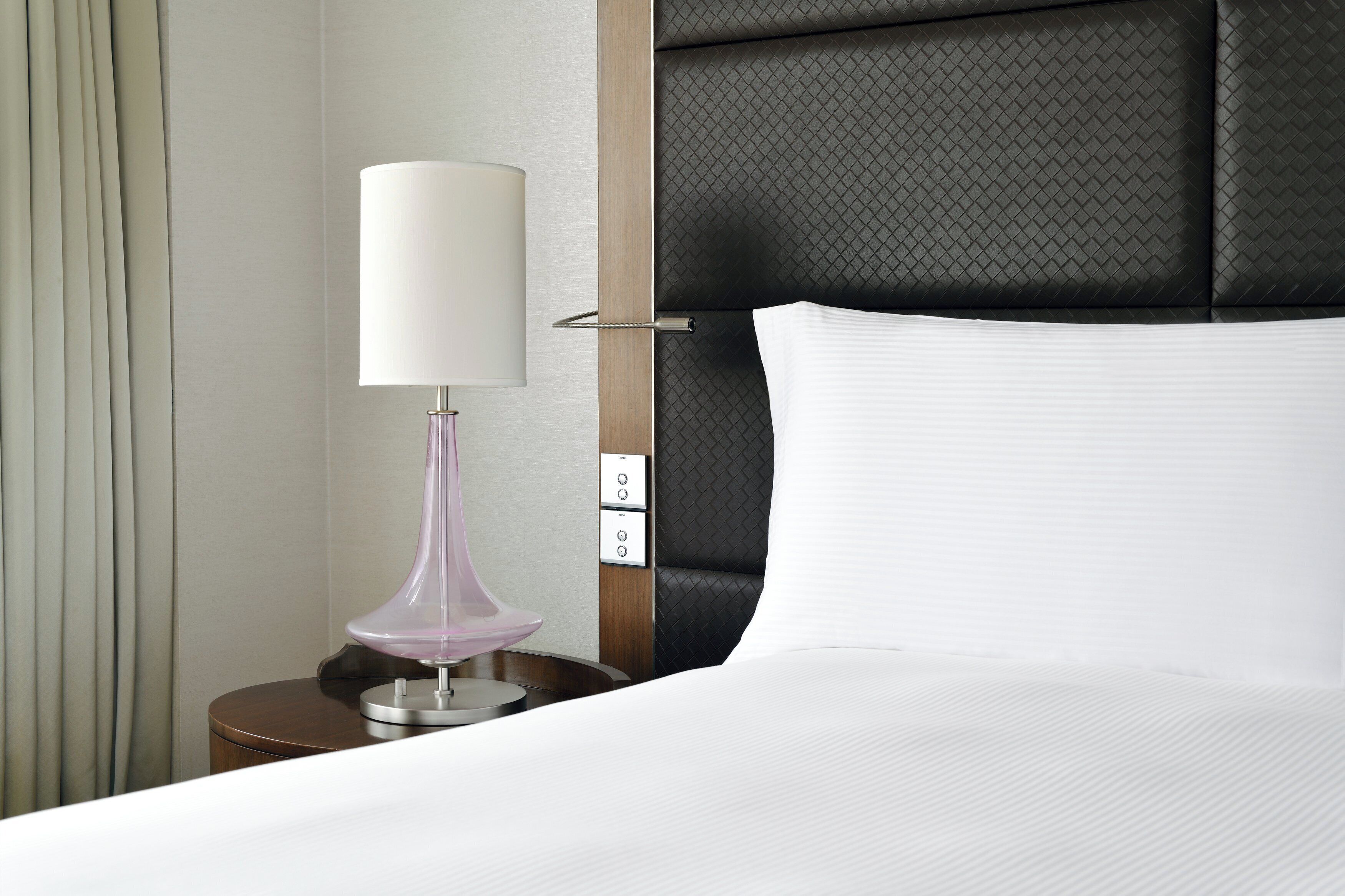 A neatly made bed with a white pillow and a headboard with a textured pattern.