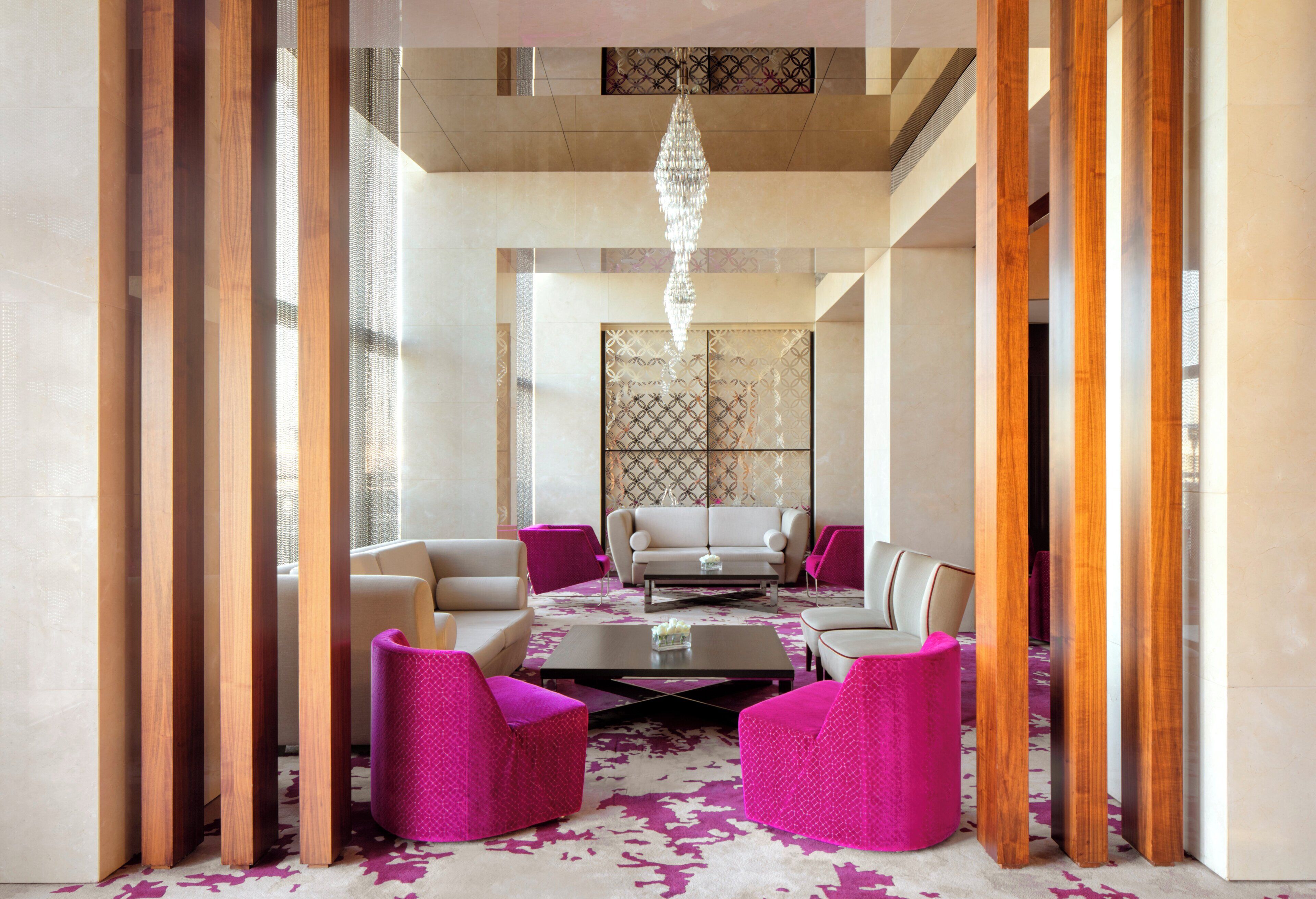 A modern lounge area with a sofa, armchairs, and a coffee table, featuring a patterned carpet and a decorative wall.