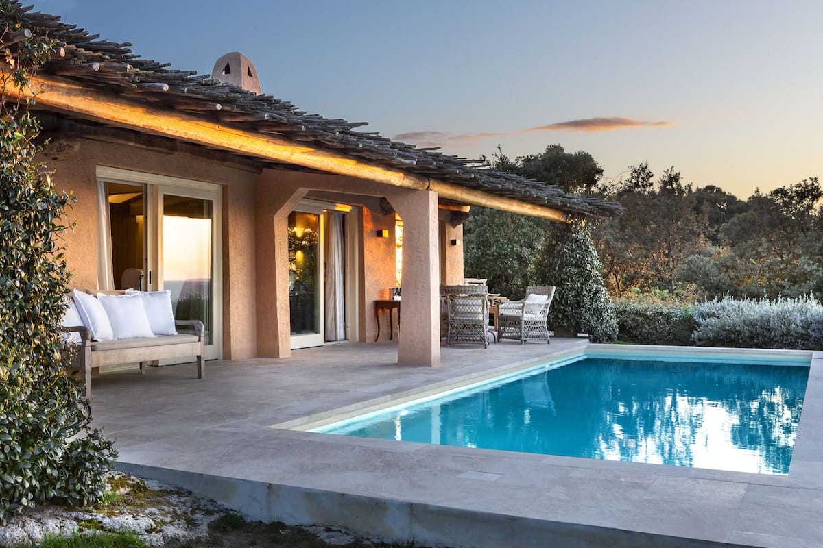 A poolside area with a patio, outdoor seating, and a view of the pool.