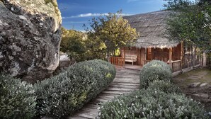 Un chalet rustique avec un toit de chaume, une terrasse en bois et un mur en pierre.