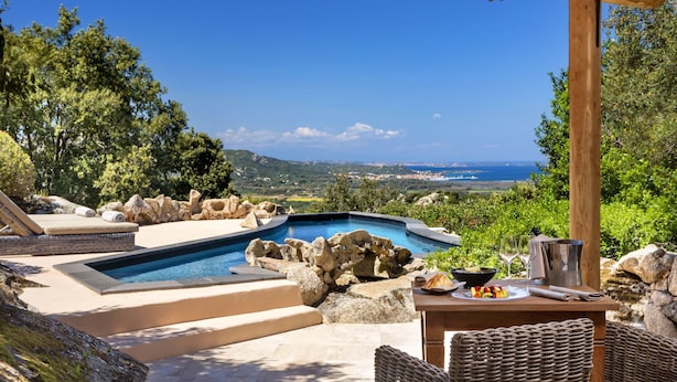 Un espace piscine avec vue sur la mer, une pergola et du mobilier d’extérieur.