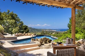 A pool area with a view of the sea, a pergola, and outdoor furniture. - Petra Segreta Resort & Spa (Olbia)