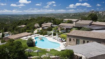 A villa with a swimming pool, surrounded by lush greenery and a view of distant mountains.