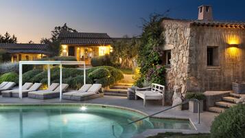 Relax by the serene pool surrounded by a beautifully maintained garden and lounge chairs.