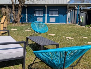A patio area with a blue chair, a small table, and a sofa.