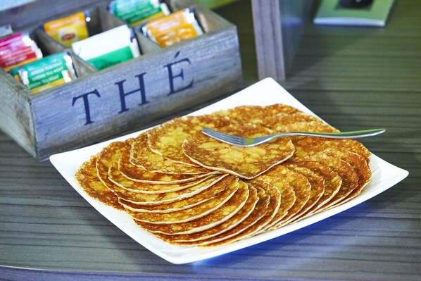 A plate of pancakes on a table with a wooden box labeled "THE" in the background.