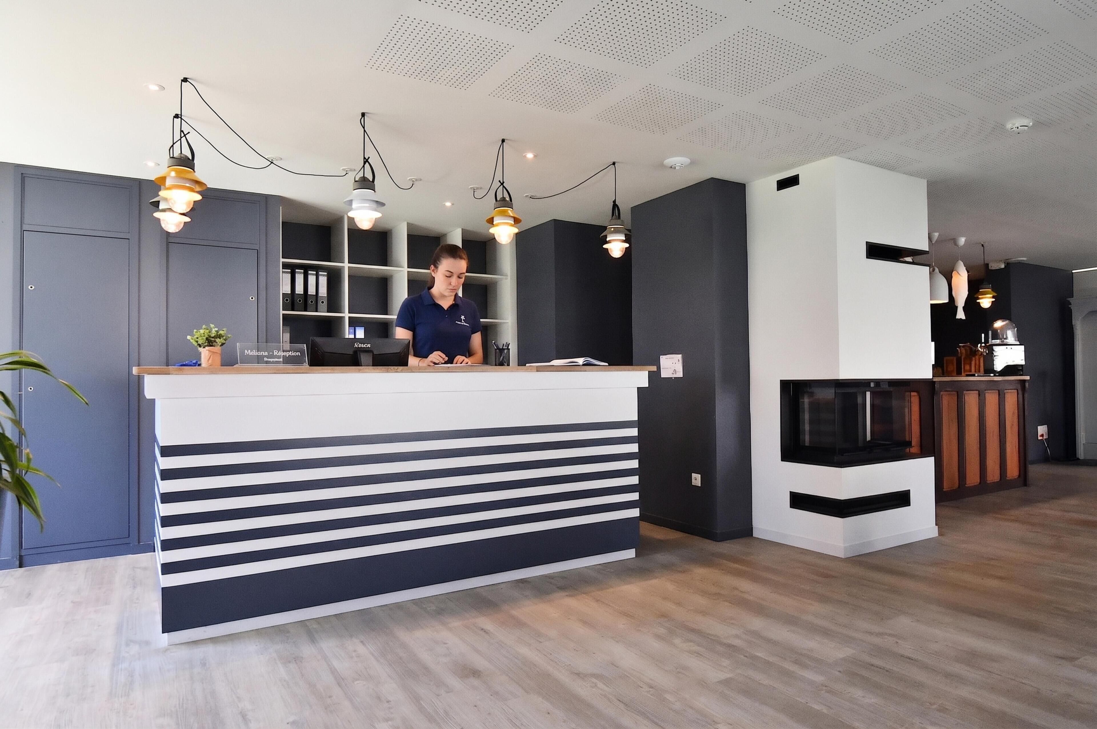 A reception desk with a modern design, a receptionist, and a counter with a plant.