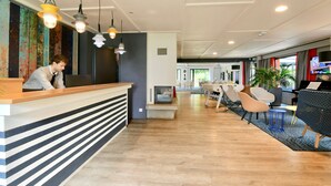 A reception area with a counter, chairs, and a piano. - Kyriad Lannion (Lannion)