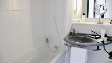 Une salle de bain moderne avec une baignoire, un lavabo en granit, une douchette à main et un miroir.