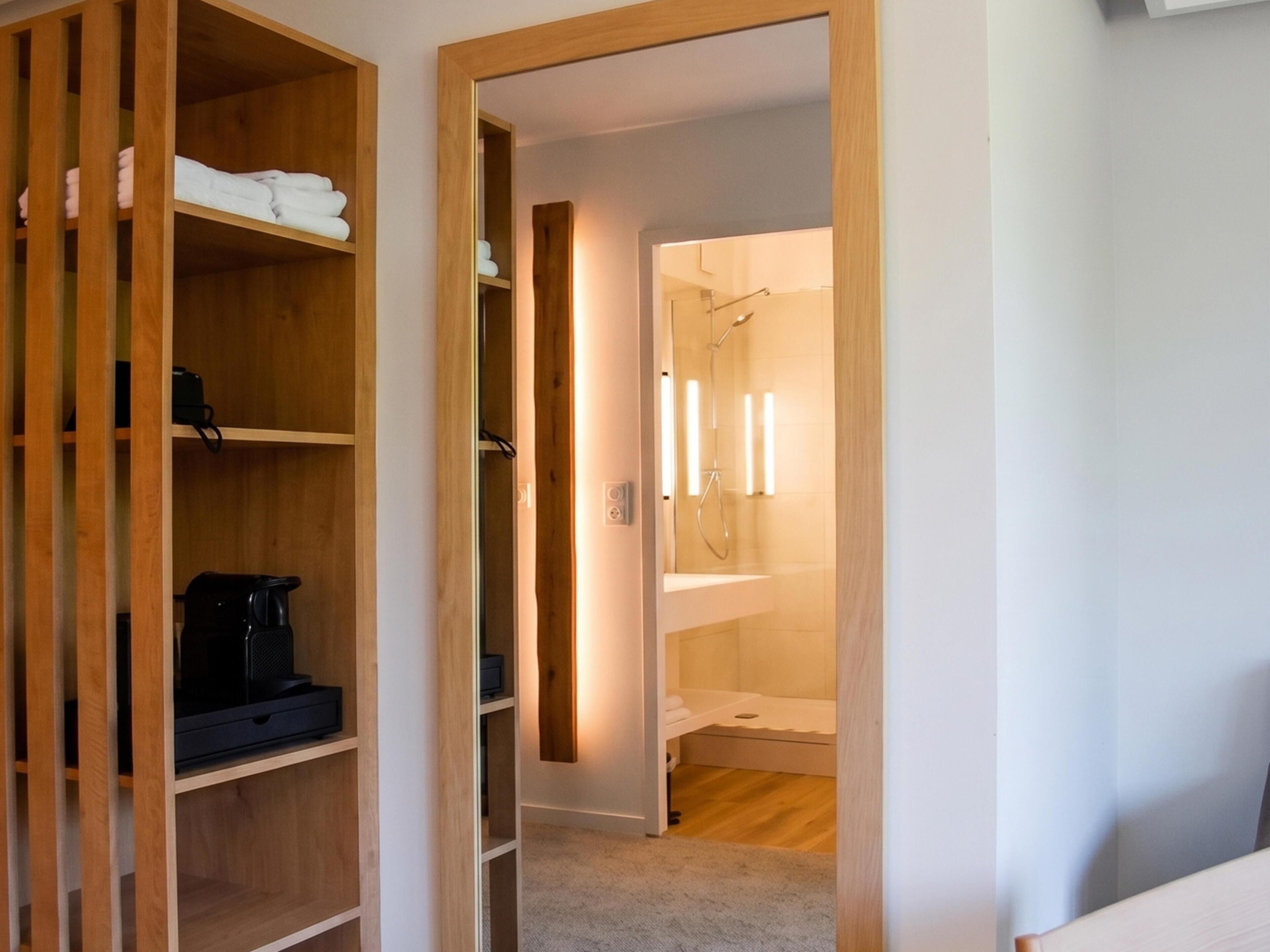 A walk-in closet with shelves and a hanging rod, a small coffee maker, and a shelf with folded towels.