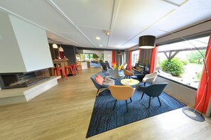 A modern living room with a fireplace, seating area, and large windows. - Kyriad Lannion (Lannion)
