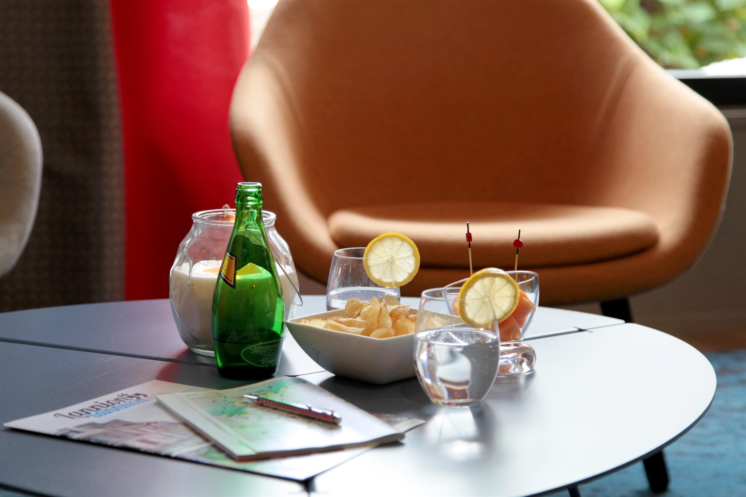 A table with a bowl of snacks, a bottle, glasses, and a candle.