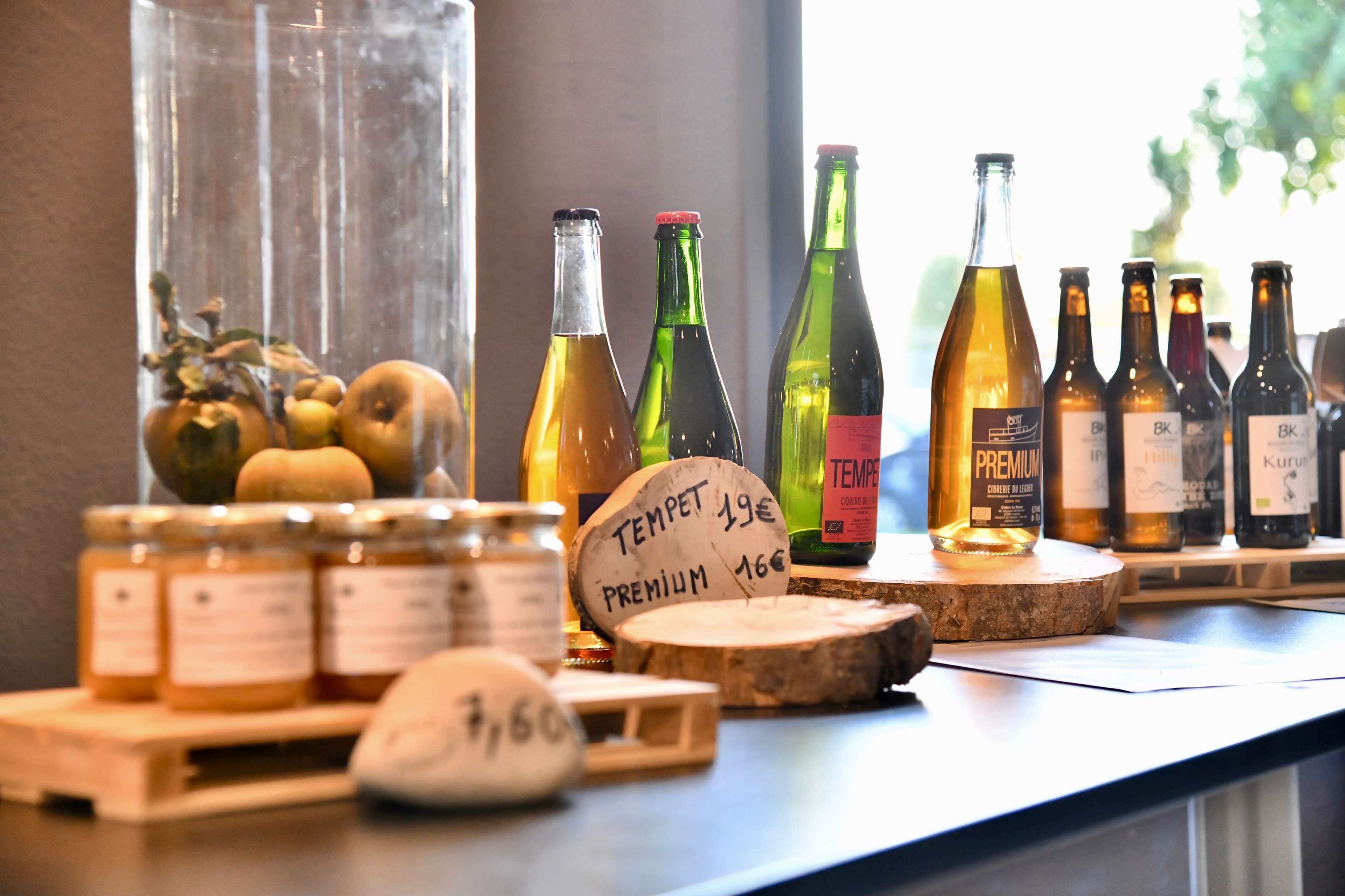 A bar counter with various bottles of alcohol, a jar of honey, and a wooden cutting board with a price tag.