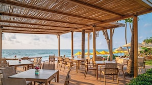 A wooden deck with tables and chairs, overlooking the ocean. - Buri Rasa Village Samui Adults Only (Koh Samui)