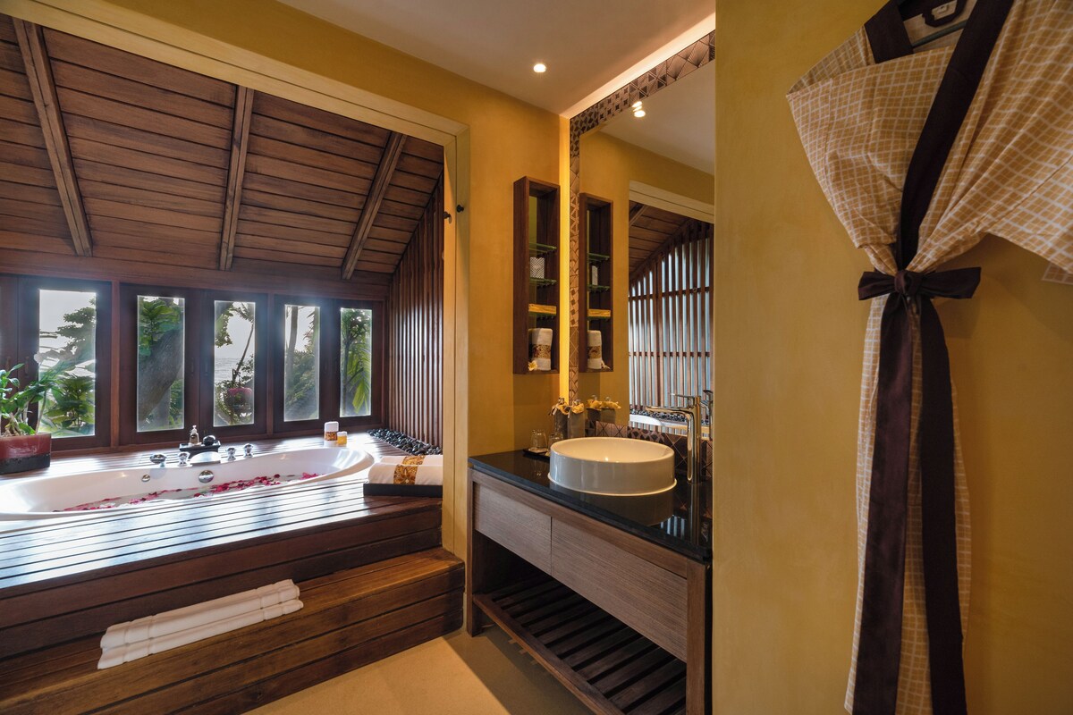 Ein Badezimmer mit einer großen Badewanne, einem Holzkosmetikschrank und einem Spiegel.