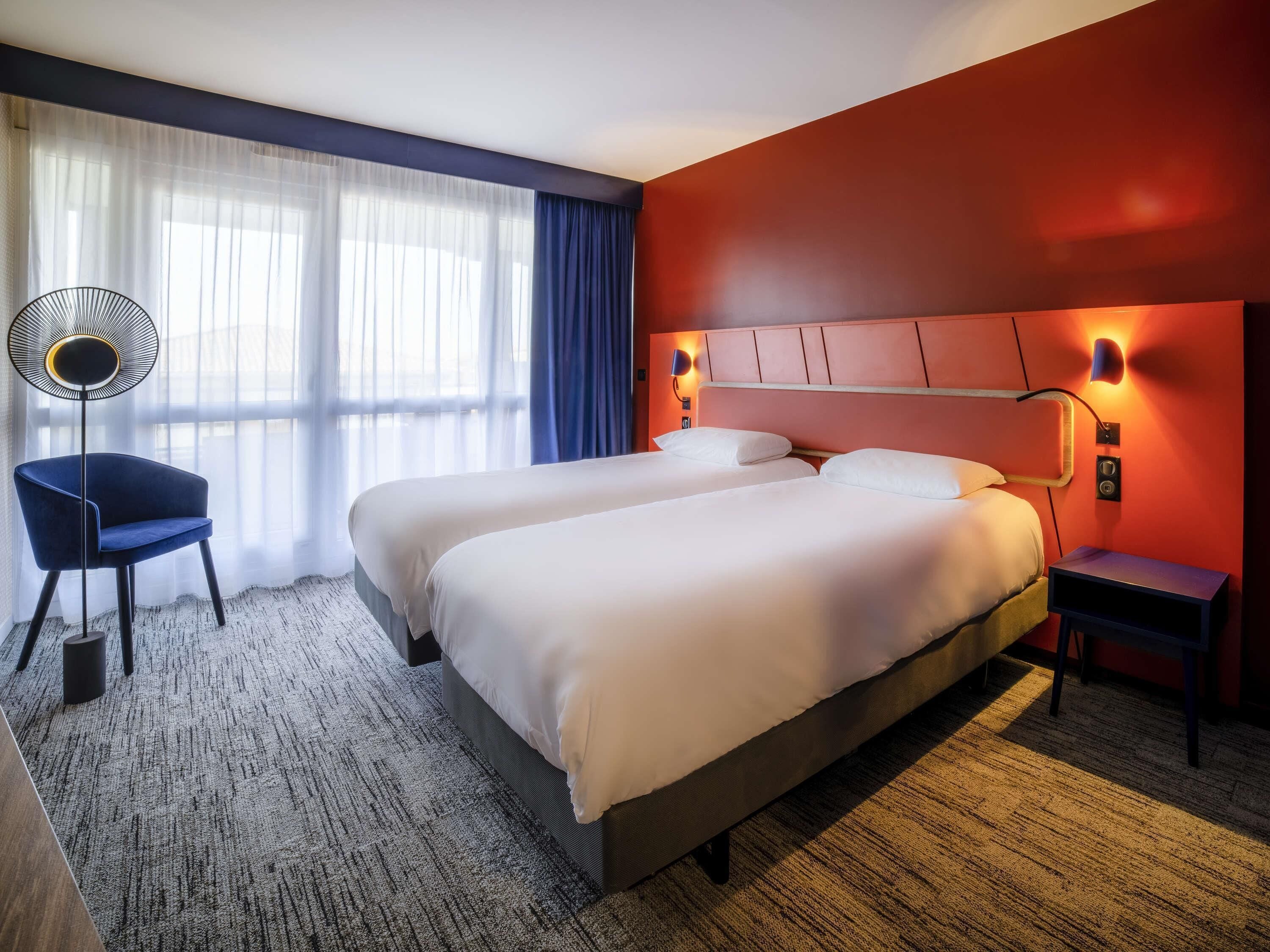 Une chambre d’hôtel avec un grand lit, une chaise, un bureau et une lampe.