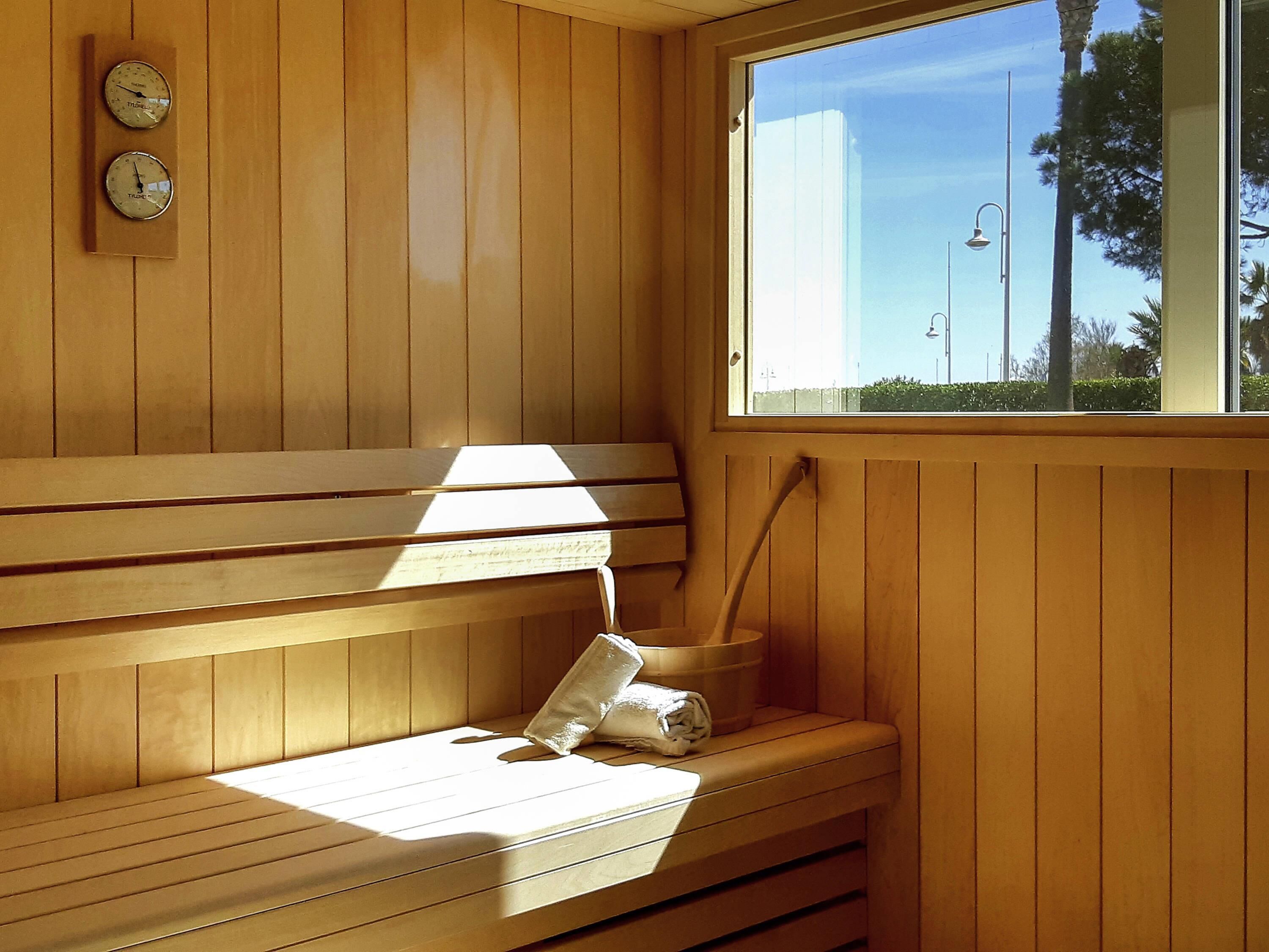 Un sauna en bois avec des bancs, une fenêtre et un porte-serviettes.