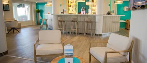 A modern bar area with high stools, a wooden reception desk, and a bar counter.