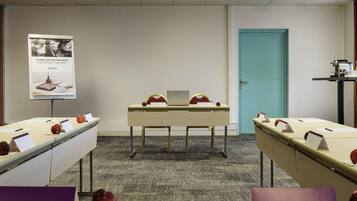 A conference room with a long table, nameplates, and apples. There is a poster on the wall and a door in the background.