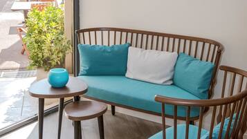 Un banco de madera con cojines color turquesa, una mesita redonda con un cuenco azul y una planta en maceta.