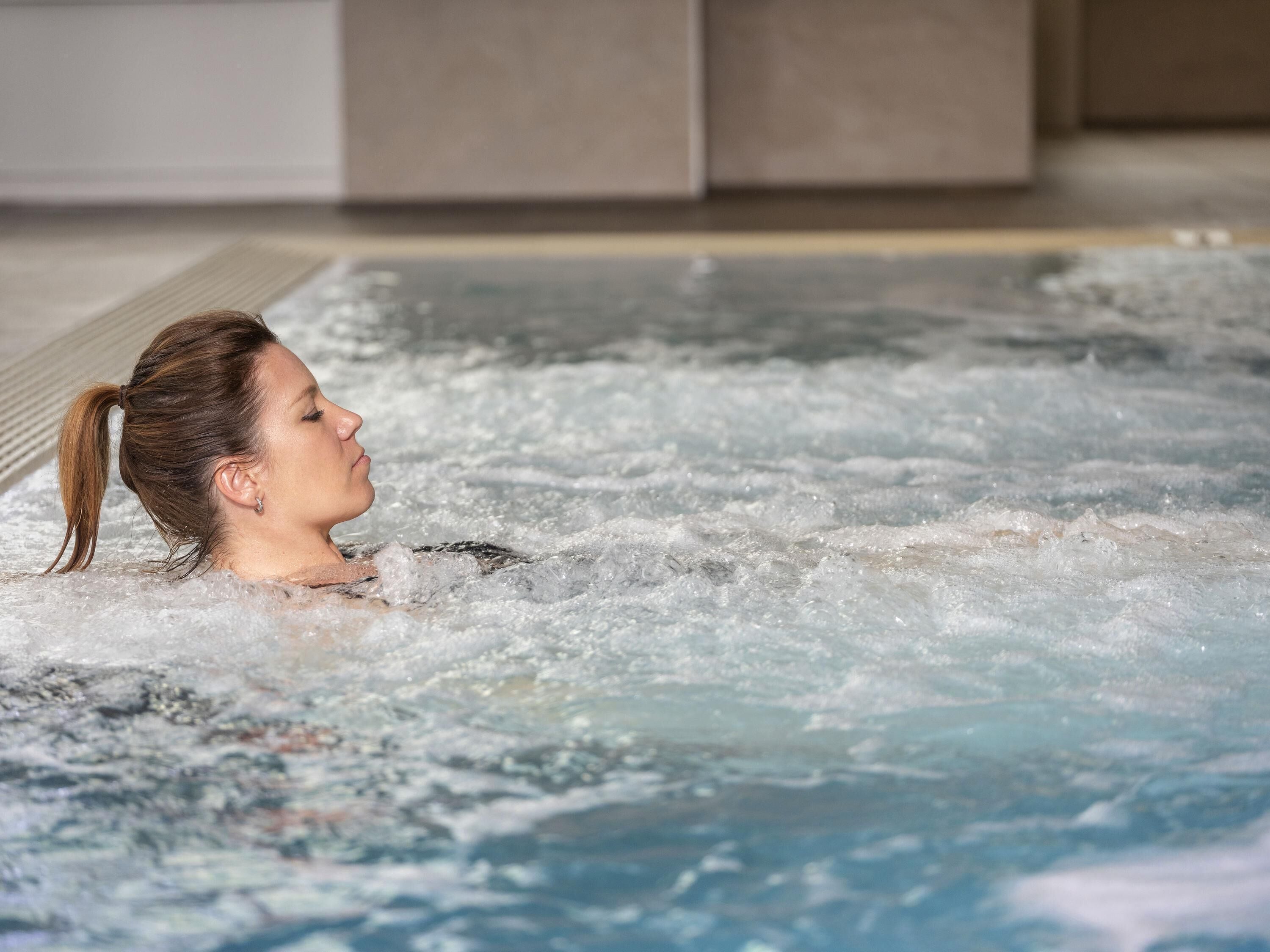 A person in a hot tub with visible bubbles and water.