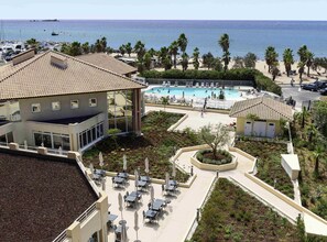 A resort with a swimming pool, outdoor seating, and a view of the sea.