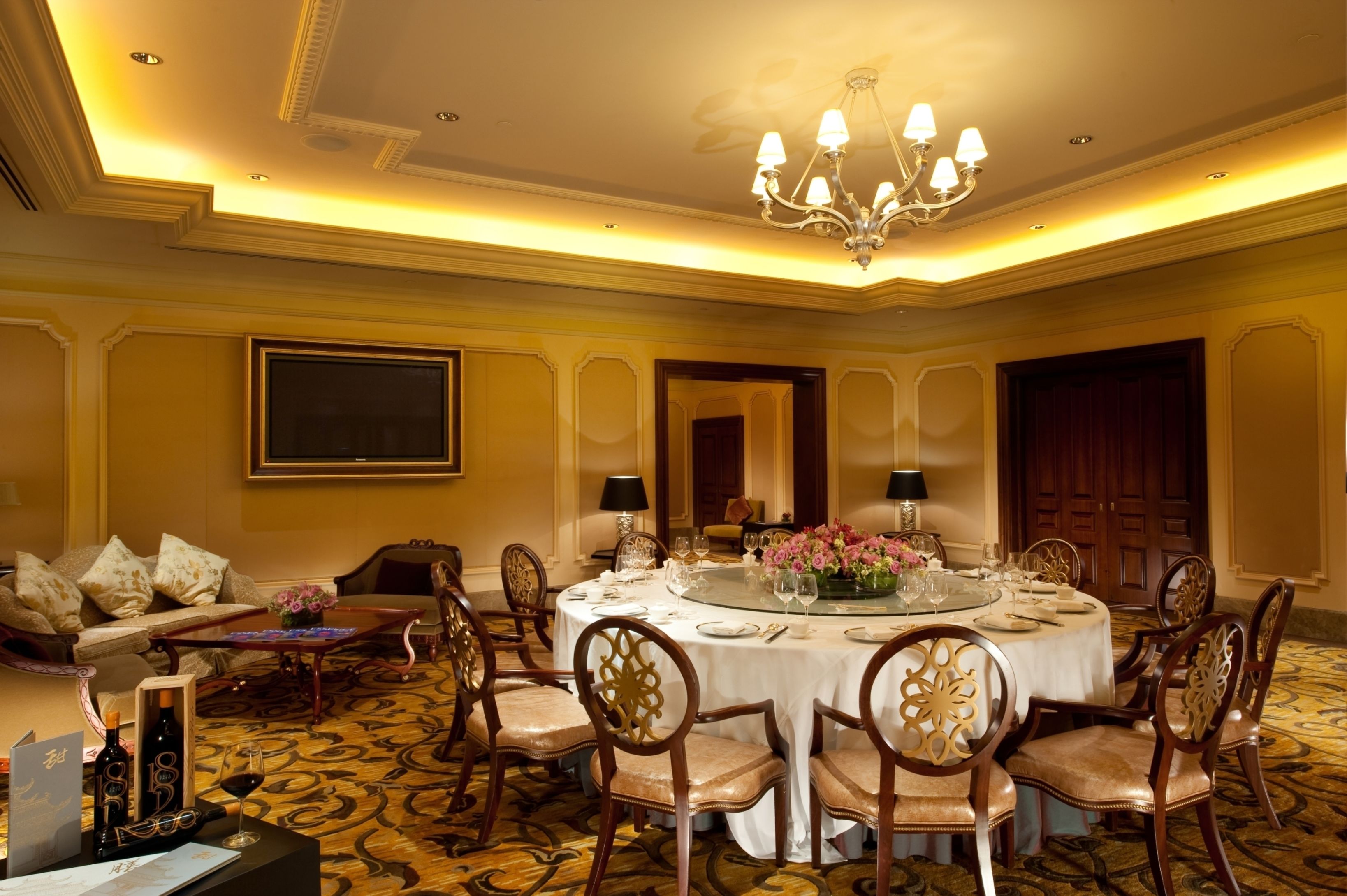 A formal dining room with a round table, chairs, and a chandelier.