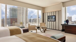 A modern hotel room with large windows, a bed, a chair, a small table, and a TV on the wall. - MGM MACAU (Macau)