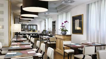 A spacious dining area with multiple tables and chairs, a central bar area, and a view of the kitchen in the background.