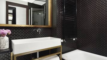 A modern bathroom with a white sink, a bathtub, and a large mirror.