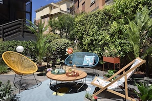 An outdoor patio area with a round table, two chairs, and a small easel.