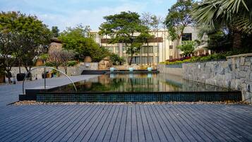 A swimming pool with a stone border, surrounded by a wooden deck and various plants.