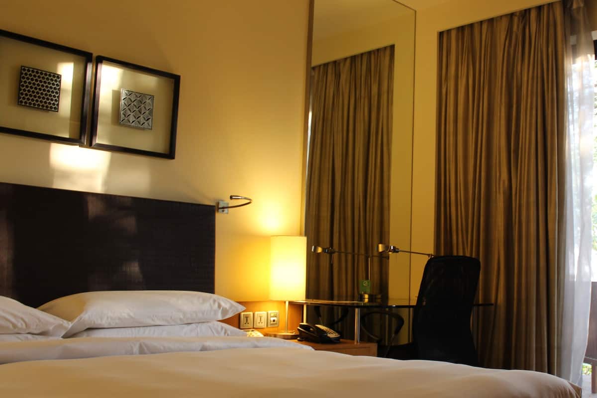 A hotel room with a large bed, a desk with a lamp, a chair, and a large mirror.