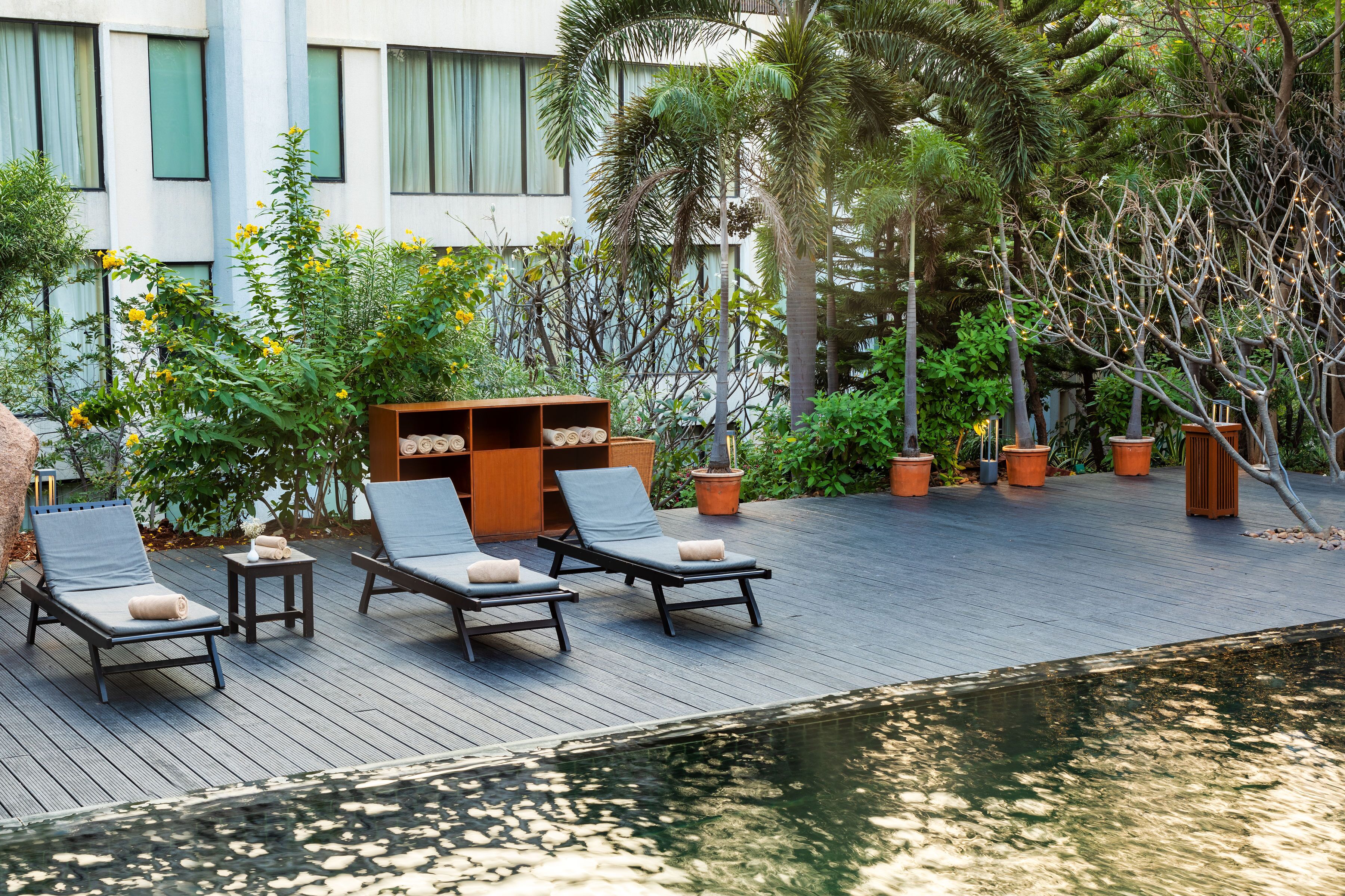 Una piscina al aire libre, sombrillas, sillones reclinables de piscina