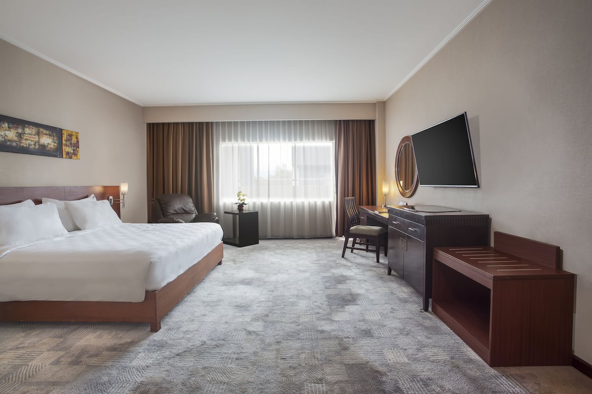 Une chambre d’hôtel équipée d’un lit, d’un bureau, d’une chaise, d’une télévision et de rideaux.