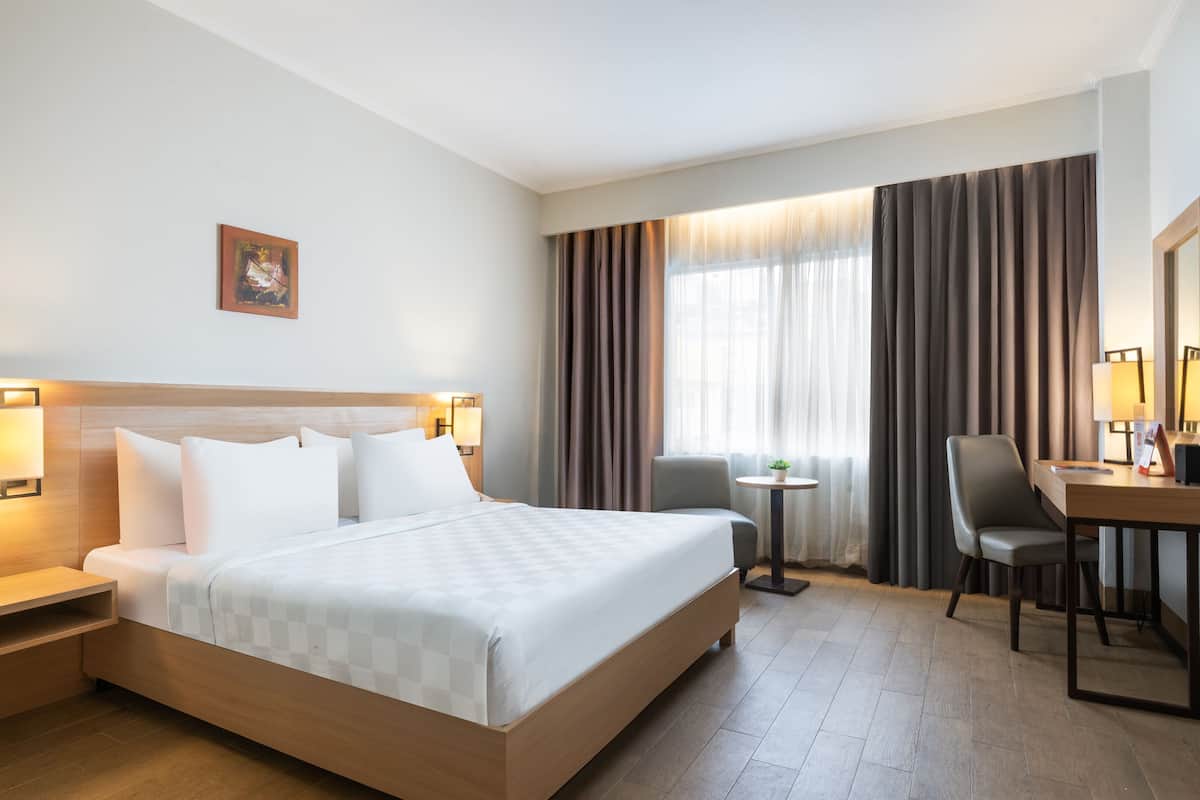 Une chambre d’hôtel avec un grand lit, des tables de chevet, un bureau, une chaise et un téléviseur.