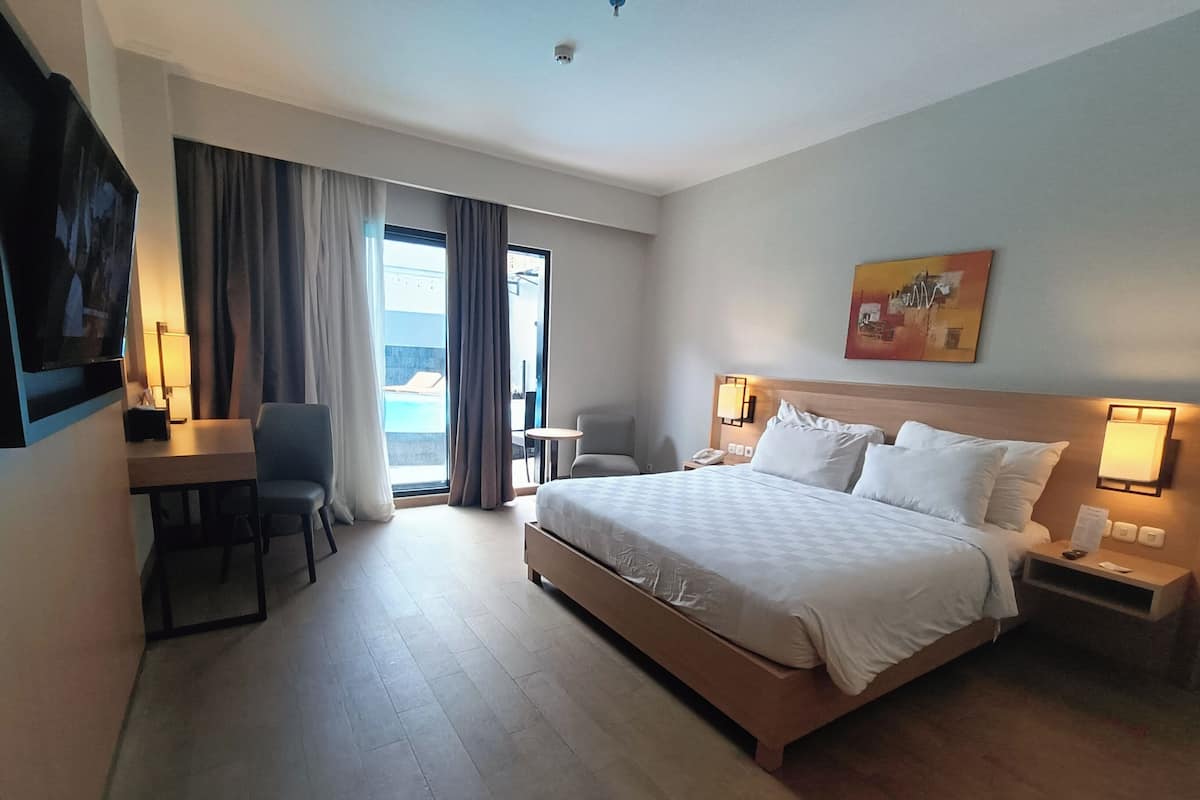 Une chambre d’hôtel avec un lit, un bureau, une chaise et une vue sur l’extérieur.