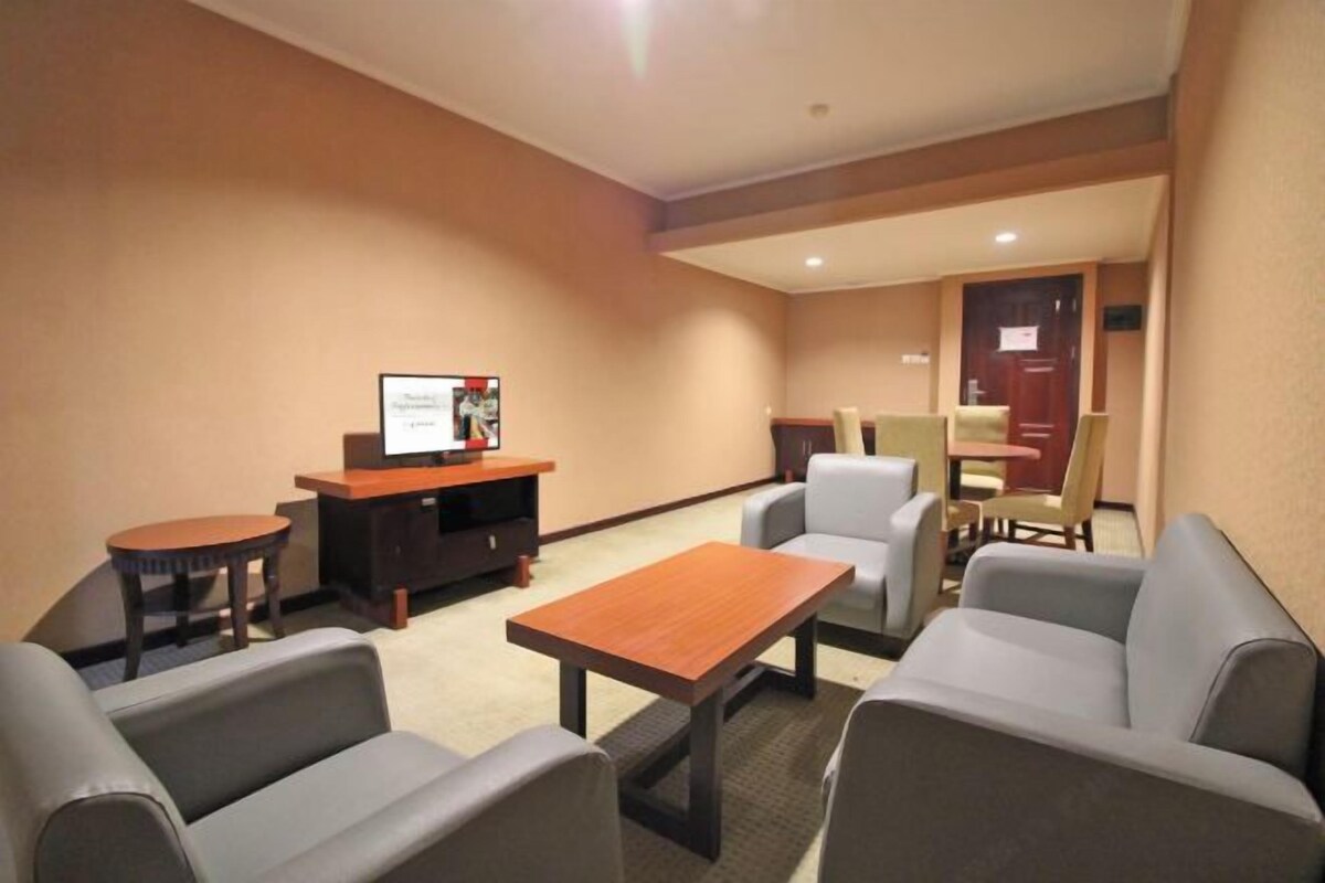Ein Hotelzimmer mit einer Sitzecke, einem Fernseher und einem Schreibtisch.