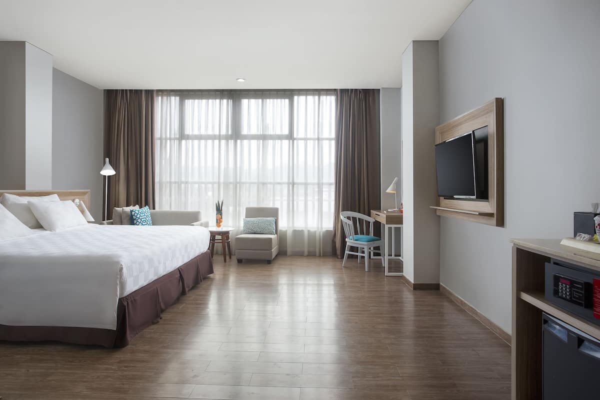 Une chambre d’hôtel moderne équipée d’un grand lit, d’un bureau, d’une chaise et d’un téléviseur.