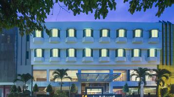 A modern hotel with a prominent entrance, multiple balconies, and a sign indicating it is the Swiss Belhotel Manokwari.