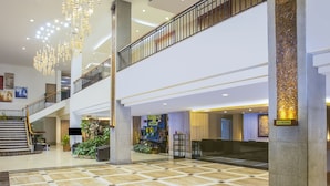 Eine geräumige Lobby mit Schachbrettboden, einer Treppe und einer dekorativen Leuchte.